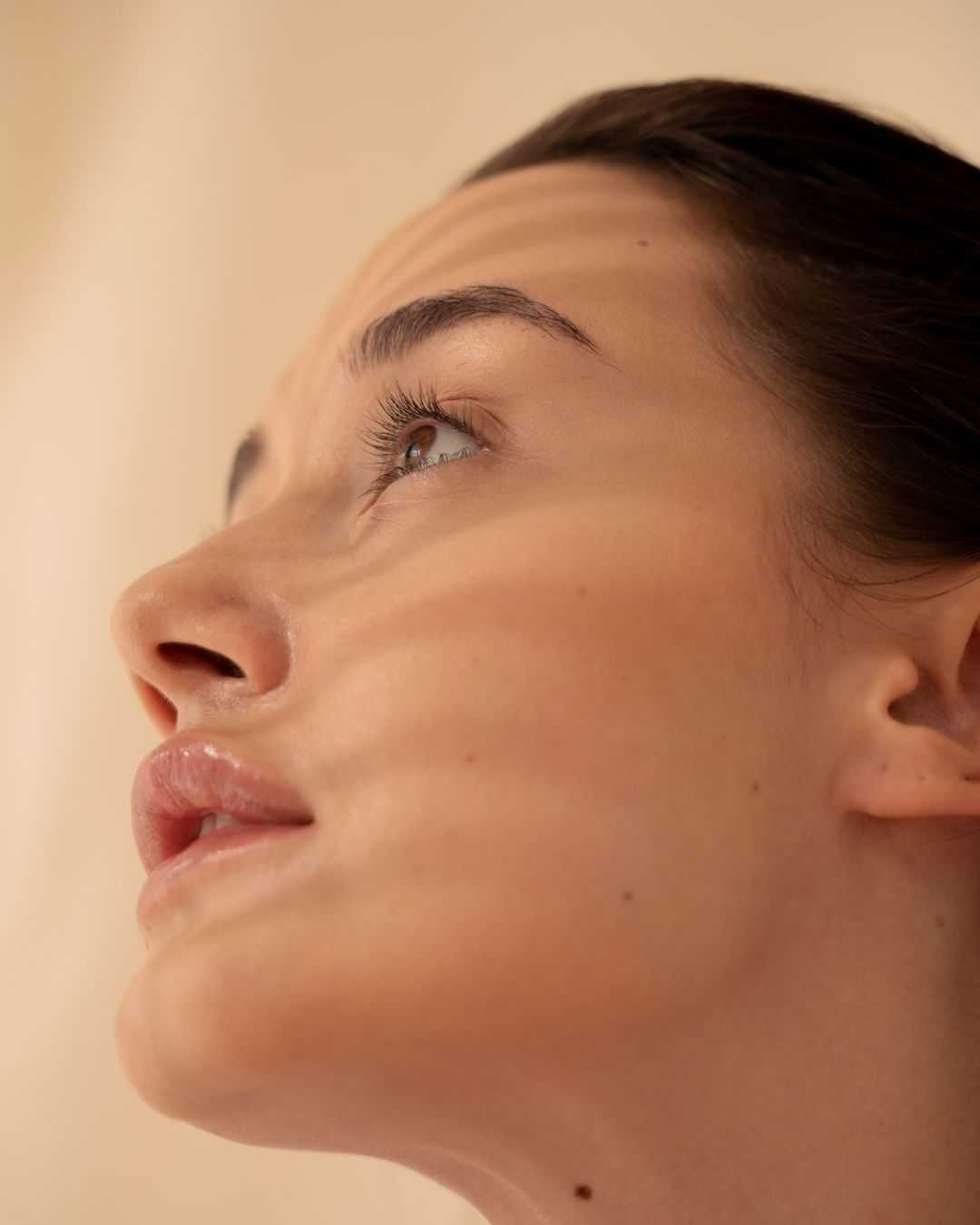 Close-up of a woman's face gazing upward with shadows highlighting her features.